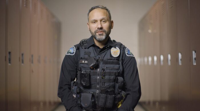 A police officer stands in a hallway.