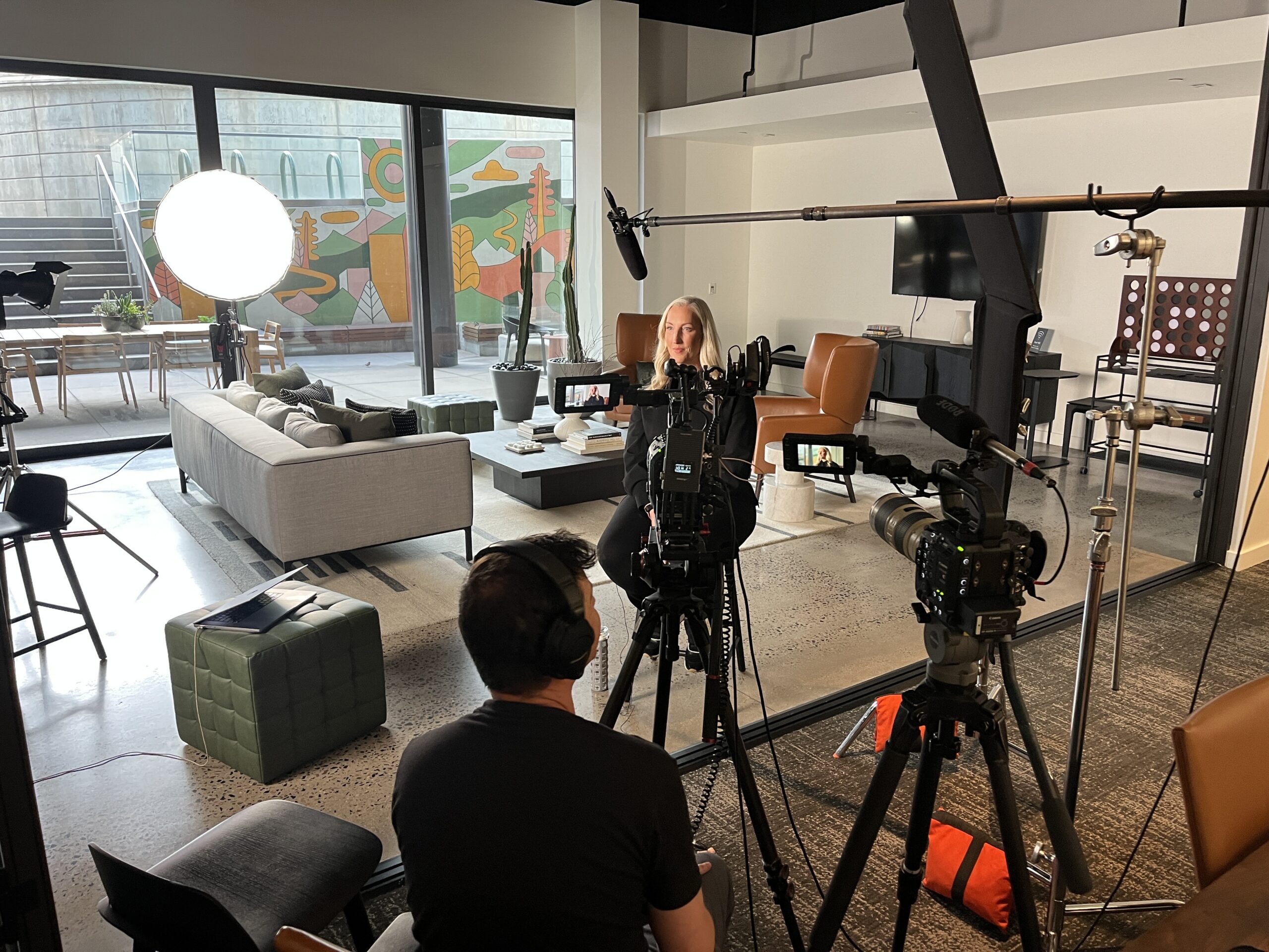 A production crew and cameras around an interview subject in an office lobby area
